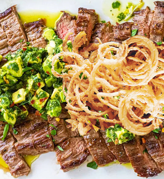 Grilled Flank Steak, with Ancho Chili, Coffee, Bean, Coriander, and Cocoa Rub, Smoky Avocado Chimichurri Sauce, and Crisp Fried Onion Strings